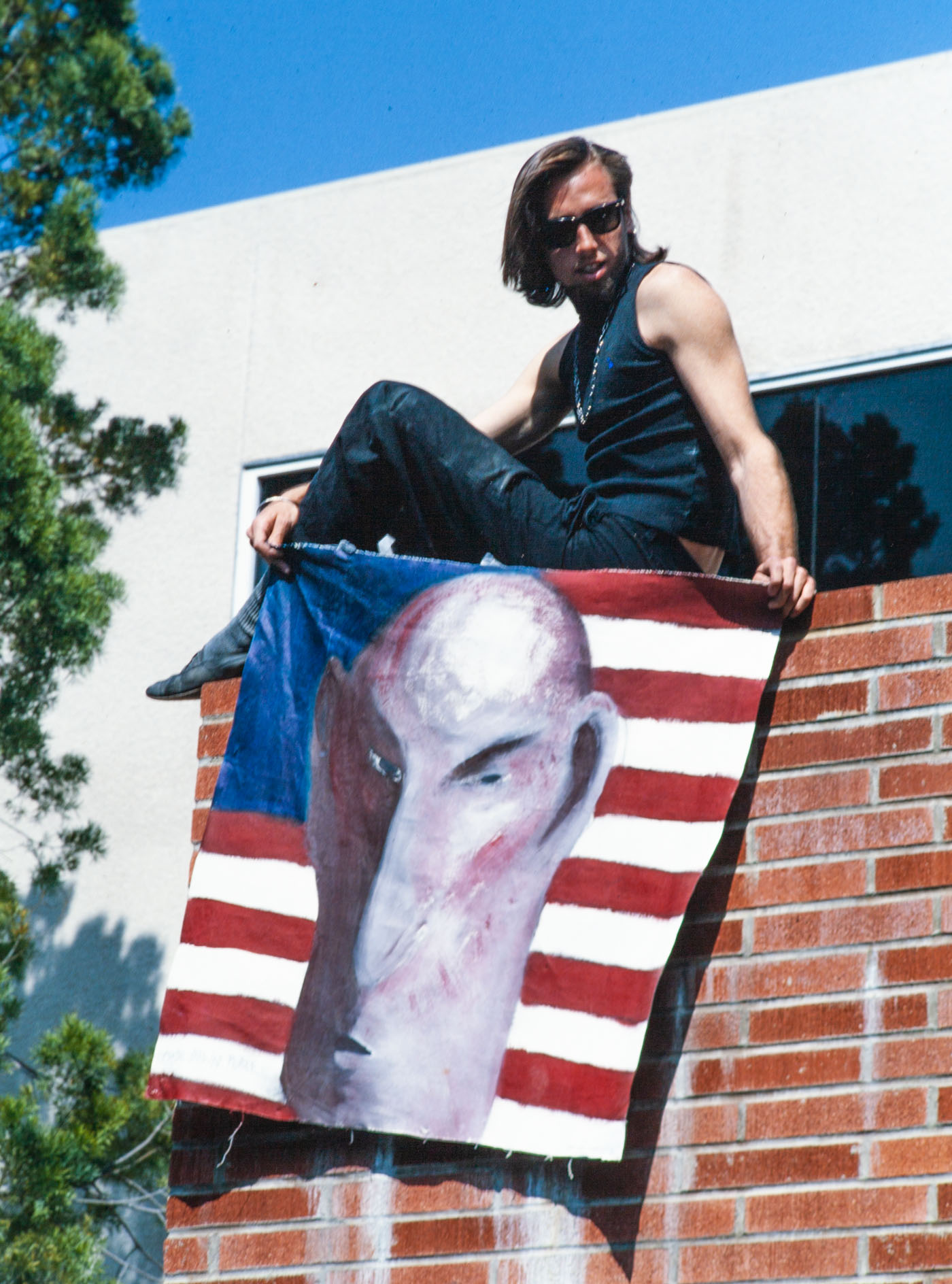 Photo of Luther Thie at Anti-Apartheid Protest at UCLA with Mutant Flag Painting, 1985